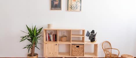 A wooden shelf with books, a potted plant, and a wicker basket.