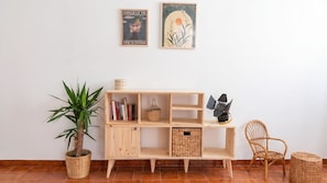 A wooden shelf with books, a potted plant, and a wicker basket. - Chez Mich - Two Bedroom Apartment, Sleeps 5 (Alghero)