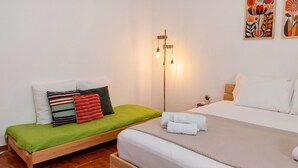 A bedroom with a single bed, a green mattress, and a wooden headboard. There is a bedside table with a lamp and a small plant. - Chez Mich - Two Bedroom Apartment, Sleeps 5 (Alghero)