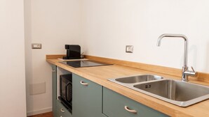 A compact kitchenette with a double sink, a coffee maker, and a microwave. - Chez Mich - Two Bedroom Apartment, Sleeps 5 (Alghero)