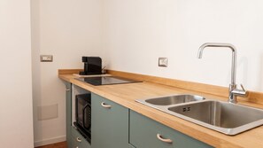 A compact kitchenette with a double sink, a coffee maker, and a microwave. - Chez Mich - Two Bedroom Apartment, Sleeps 5 (Alghero)