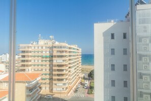 A multi-story building with balconies, a parking area, and a view of the sea. - Apartment Aqua Nature La Mata (Torrevieja)