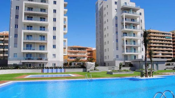 A modern hotel with a swimming pool, multiple balconies, and a well-maintained lawn. - Apartment Aqua Nature La Mata (Torrevieja)