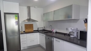 A modern kitchen with white cabinets, stainless steel appliances, and a wooden cutting board. - Apartment Aqua Nature La Mata (Torrevieja)