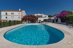 Une piscine à l’eau d’un bleu cristallin, entourée d’une terrasse dallée.