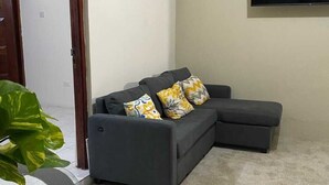 A sectional sofa with a flat-screen TV mounted on the wall above it. - Havendale Suite Retreat (Kingston)