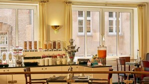 A hotel bar with a counter displaying various food items and a coffee machine. There are chairs around the bar and a view of the city through large windows. - 2 Person Holiday Park Home in Stade (Stade)