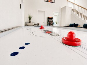 A shuffleboard table in a room with a staircase and a door leading to another room. - Beachfront, Hot Tub, Arcade, Foosball, Steps to beach, outdoor games & MORE (Galveston)