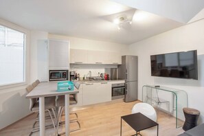 Eine moderne Küche mit Essbereich, einer Mikrowelle, einer Kaffeemaschine und einem an der Wand befestigten Fernseher.