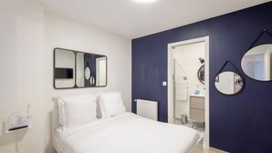 Ein Schlafzimmer mit einem Bett, einem Wandspiegel und einer Tür zu einem Badezimmer.