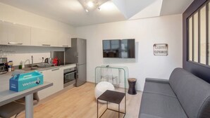 Eine moderne Küche mit Einbauofen und Essbereich, ausgestattet mit einem grauen Sofa und einem kleinen Tisch.
