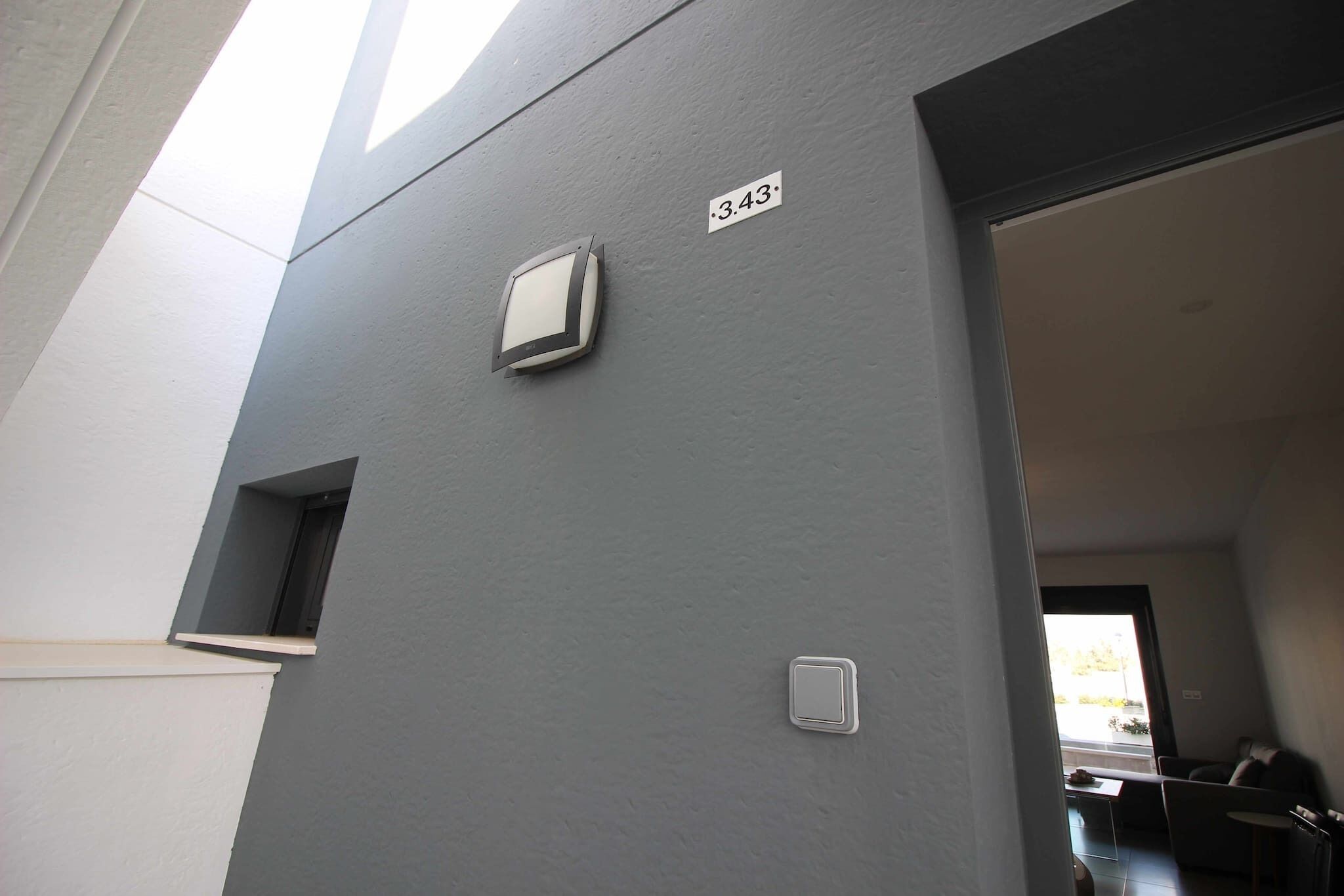 Een modern gebouw met een grijze gevel, een klein raam en een deur.