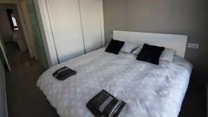 A neatly made bed with a patterned bedspread, two pillows, and a folded towel on the side. - Groundfloor Lamarii Pilar de la Horadada (Pilar de la Horadada)