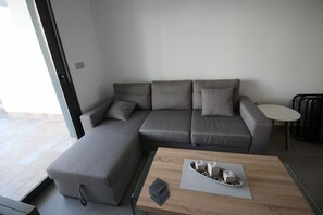 Ein modernes Wohnzimmer mit einem Ecksofa, einem kleinen runden Tisch und einem Couchtisch mit einer Auflage.