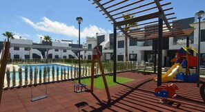Ein Poolbereich mit Rutsche und einer Pergola.