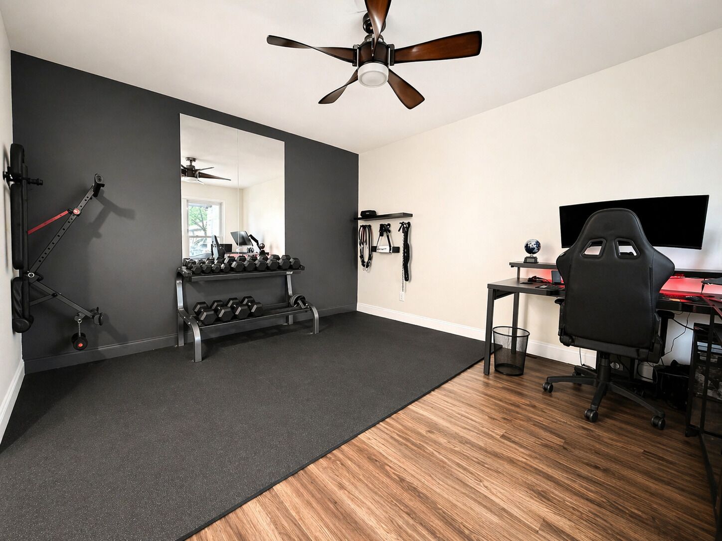 A home gym with exercise equipment, a desk with a computer, and a gaming chair.