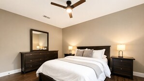 A bedroom with a bed, two nightstands, a ceiling fan, a dresser, and a mirror. - House In The Center Of The DFW Metroplex (Bedford)