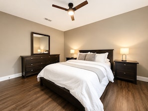 A bedroom with a bed, two nightstands, a ceiling fan, a dresser, and a mirror. - House In The Center Of The DFW Metroplex (Bedford)