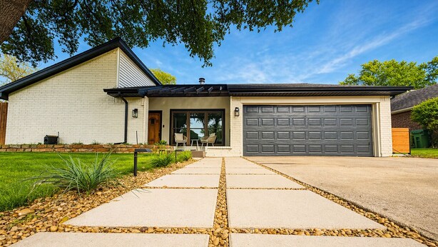 A modern two-story house with a garage, a front porch with chairs, and a landscaped driveway. - House In The Center Of The DFW Metroplex (Bedford)