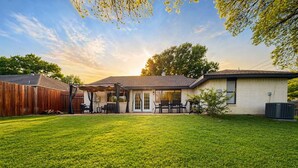 A residential backyard with a patio, a covered seating area, and a lawn. - House In The Center Of The DFW Metroplex (Bedford)