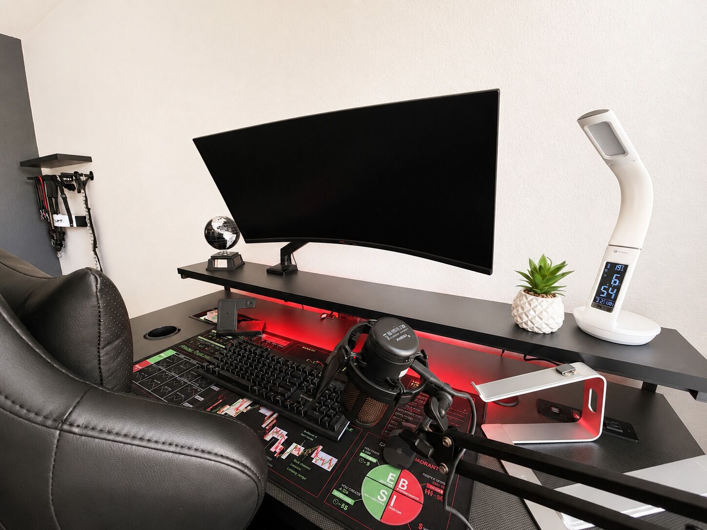 Un espace de jeu équipé d’un écran incurvé, d’un clavier mécanique et d’un bureau éclairé en rouge.