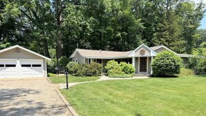 A single-story house with a garage, a front porch, and a well-maintained lawn. - Island Nights Classic Beach Cottage | Private Association Beach Access (South Haven)