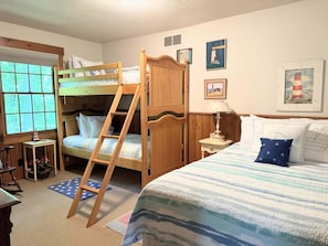 Un dormitorio con literas, una escalera, una mesita de noche, una lámpara y decoración en la pared.