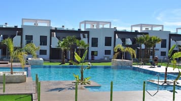 Un hôtel moderne doté d’une piscine, de palmiers et surplombant un ciel d’un bleu limpide.