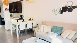A modern living room with a sofa, a coffee table, and a dining area with chairs and a table. - Penthouse Oasis Beach IV La Zenia (Orihuela)