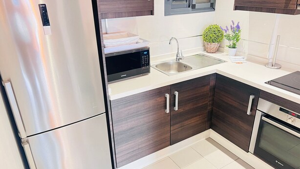 A modern kitchen with stainless steel appliances, dark wood cabinets, a microwave, and a sink. - Penthouse Oasis Beach IV La Zenia (Orihuela)