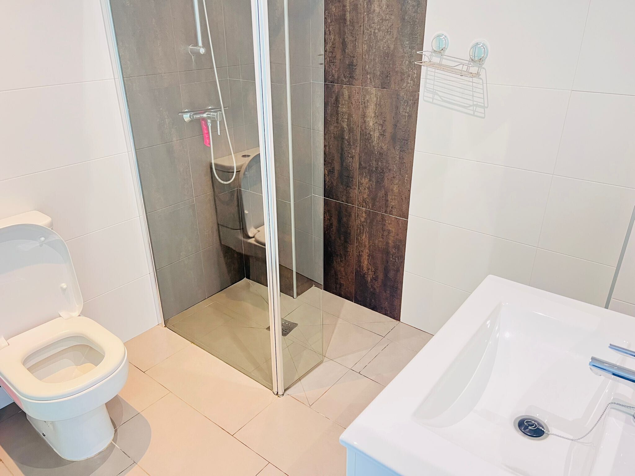 A modern bathroom with a glass-enclosed shower, a white toilet, and a white bathtub.