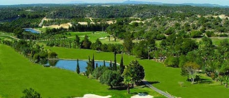 A golf course with a pond, sand bunkers, and a clear view of the surrounding landscape.