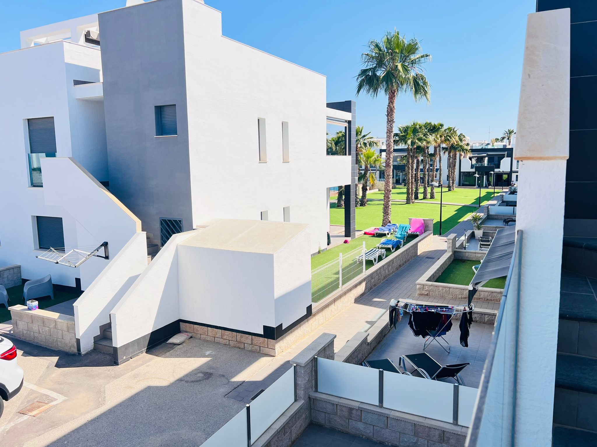 A modern building with a flat roof, a visible staircase, and a small outdoor area with a clothesline.