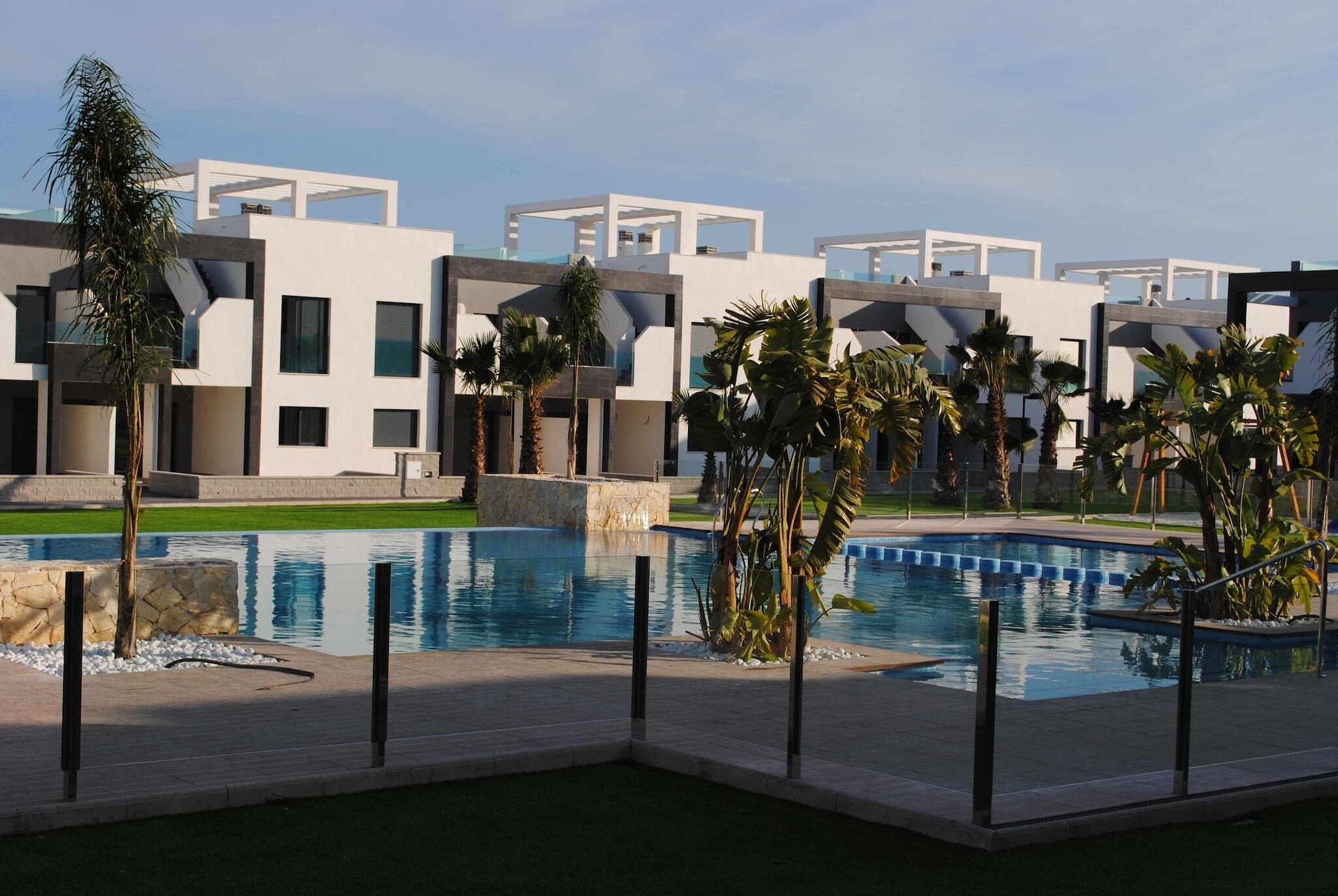 A modern hotel with a pool area, featuring contemporary architecture and palm trees.