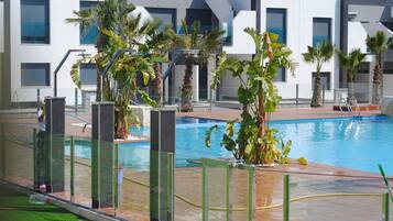 Una piscina con palmeras y un edificio moderno al fondo.