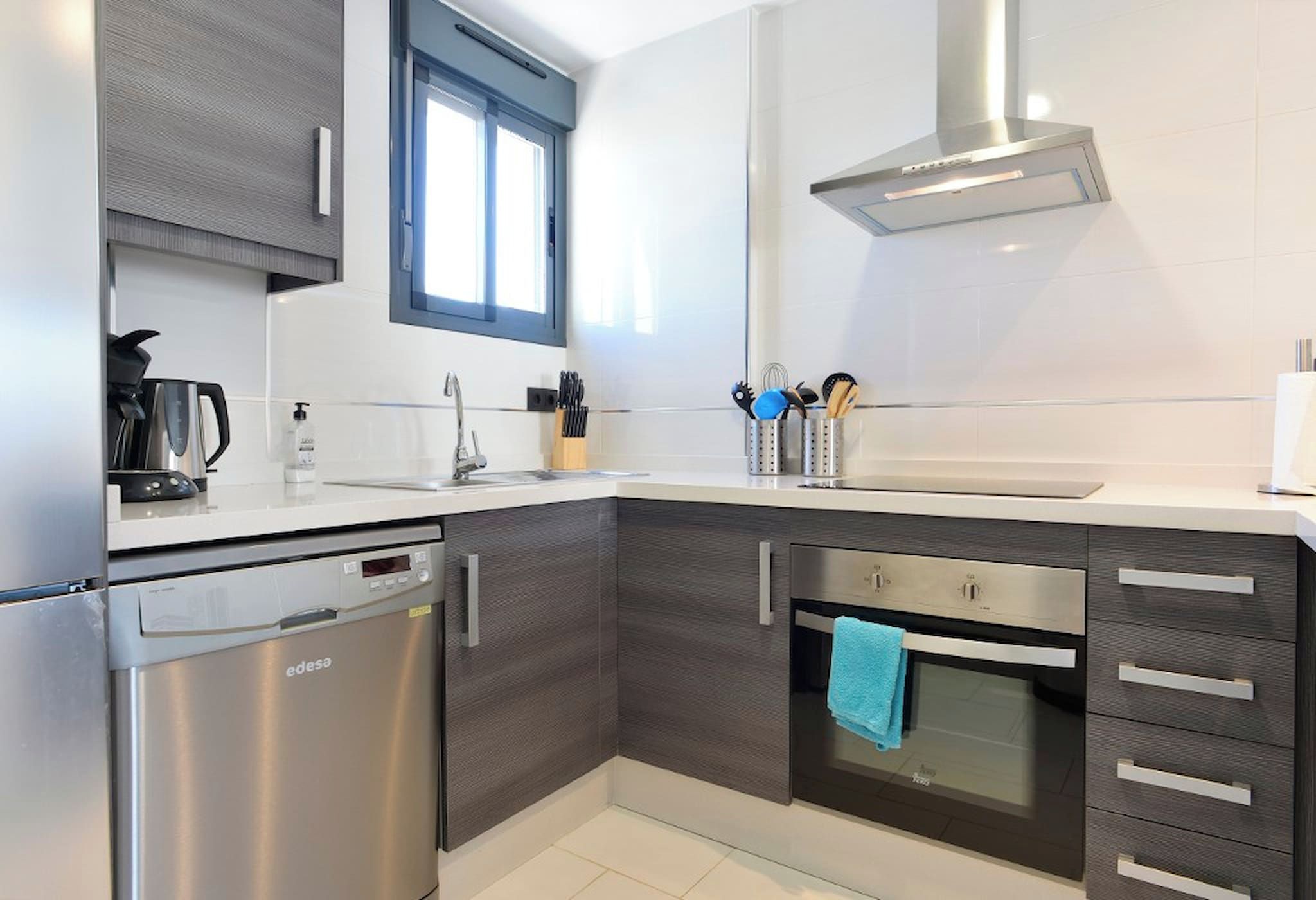 Una cocina moderna con lavavajillas, horno y una ventana sobre el fregadero.