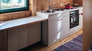 Una cocina moderna con vigas de madera, armarios blancos, un ventanal grande y un horno empotrado.