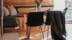 Un interior de madera con una mesa de comedor, sillas, un banco y una lámpara colgante.