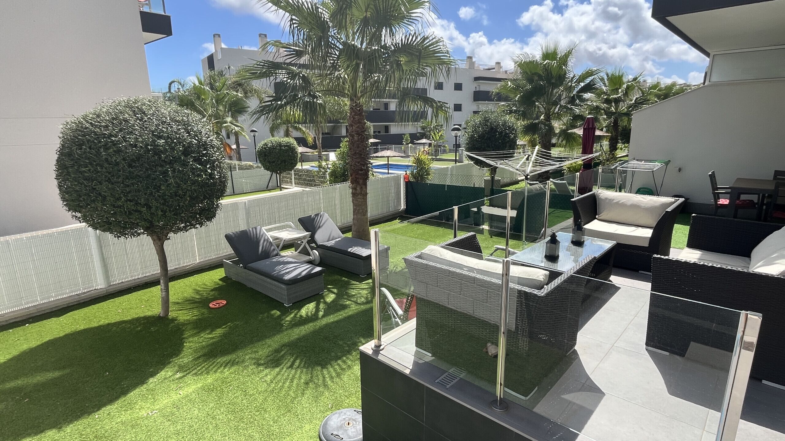 Una terraza en la azotea con mobiliario exterior, una mesa de vidrio y vistas a la ciudad.