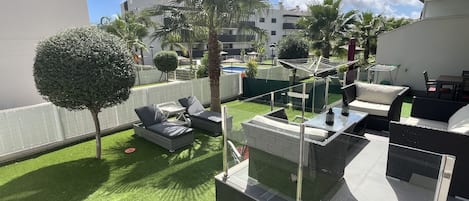 Una terraza en la azotea con mobiliario exterior, una mesa de vidrio y vistas a la ciudad.