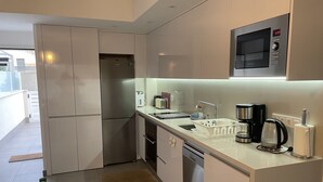 Una cocina compacta equipada con refrigerador, microondas, cafetera y lavavajillas.