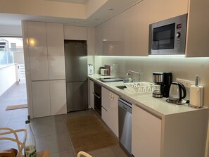Una cocina compacta equipada con refrigerador, microondas, cafetera y lavavajillas.