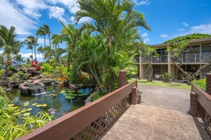 Un complexe hôtelier tropical doté d’un étang, de palmiers et d’un bâtiment avec un balcon.