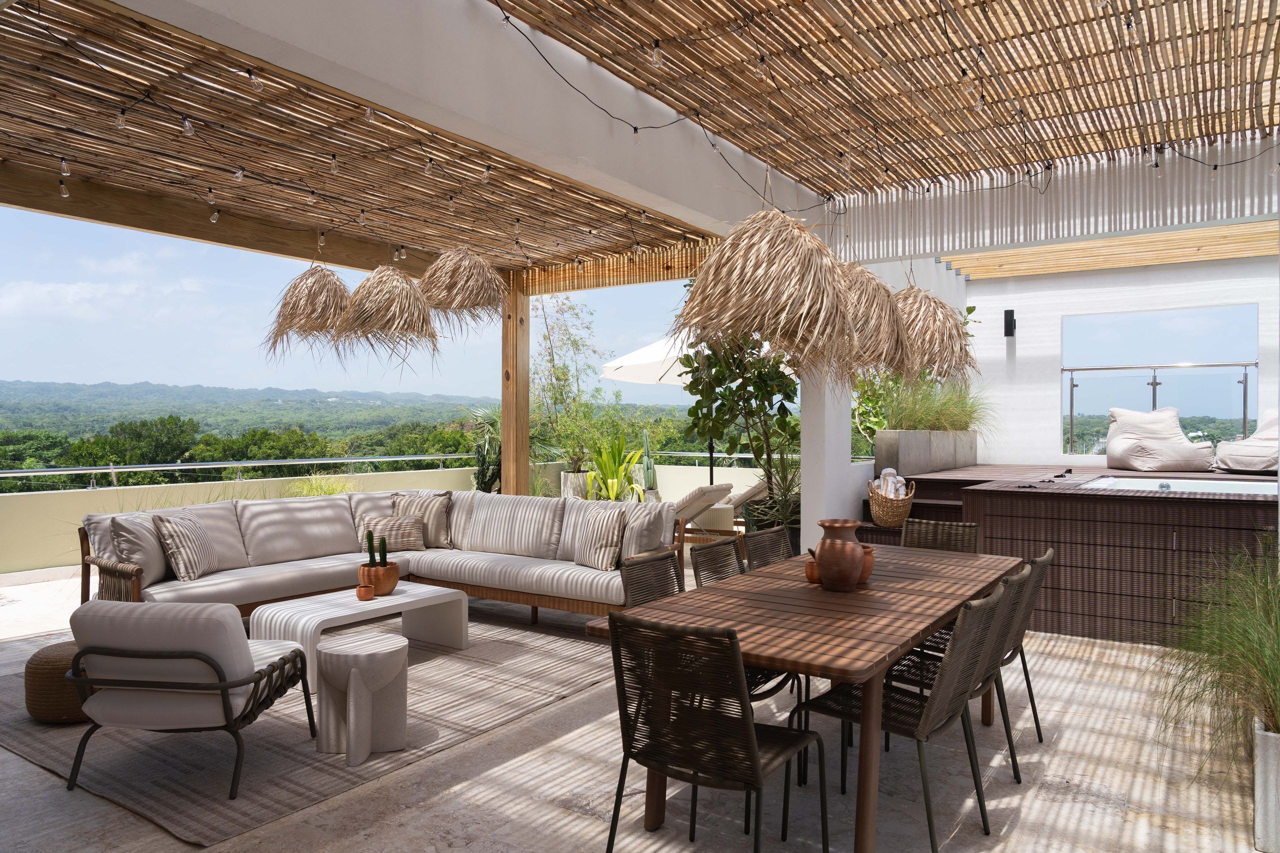 Eine Terrasse im Freien mit einer Couch, Stühlen, einem Esstisch und Blick auf die Landschaft.