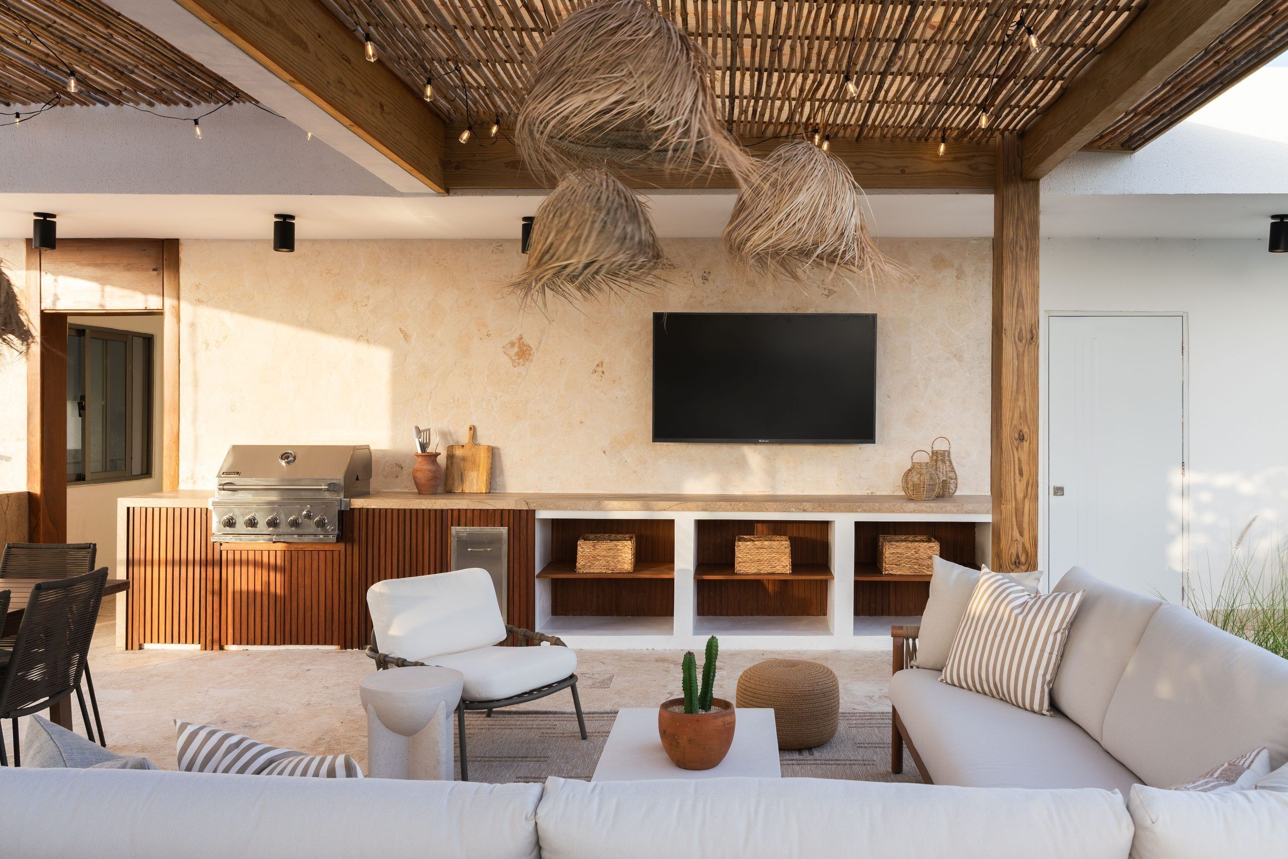Een moderne buitenruimte met een barbecue, zithoek en een wandgemonteerde flatscreen televisie.