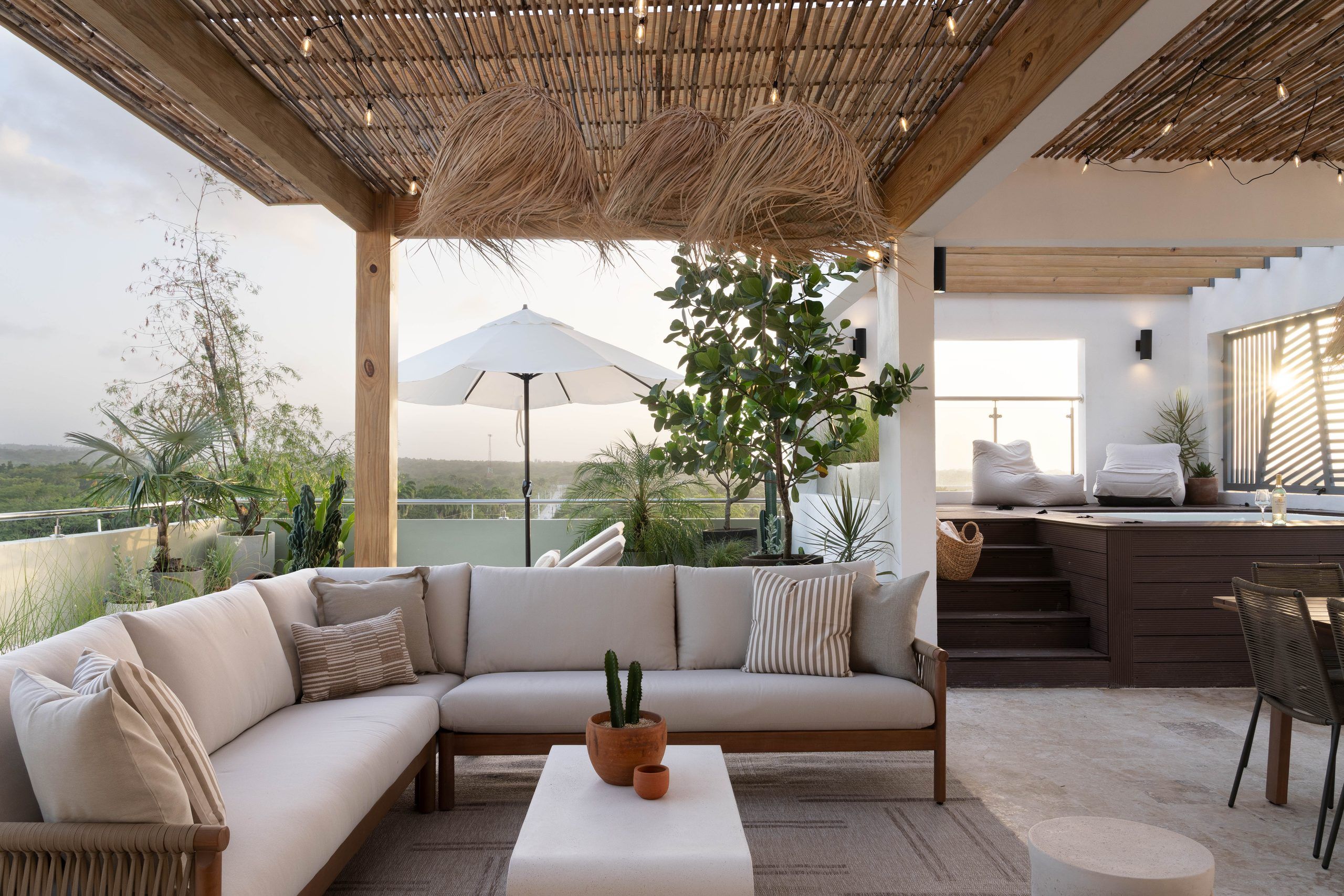 A modern outdoor seating area with a sofa, a coffee table, and a cactus plant.