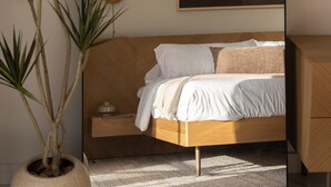 A bedroom with a bed, a bedside table, a mirror, a wall-mounted artwork, and a potted plant. - Altamar — Rooftop Penthouse, Private Jacuzzi, Walk to Encuentro Beach, Sleeps 8 (playa encuentro- cabarete)