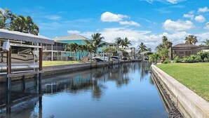 Un canal avec des bateaux, un bâtiment portant une enseigne « GOLDEN 888-999-LIFT », et des palmiers.