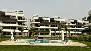 Ein modernes Hotel mit Schwimmbad, mehreren Balkonen und einem gepflegten Rasen.