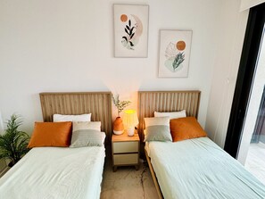 Une chambre d’hôtel avec deux lits, une table de chevet avec une lampe et deux œuvres d’art accrochées au mur.